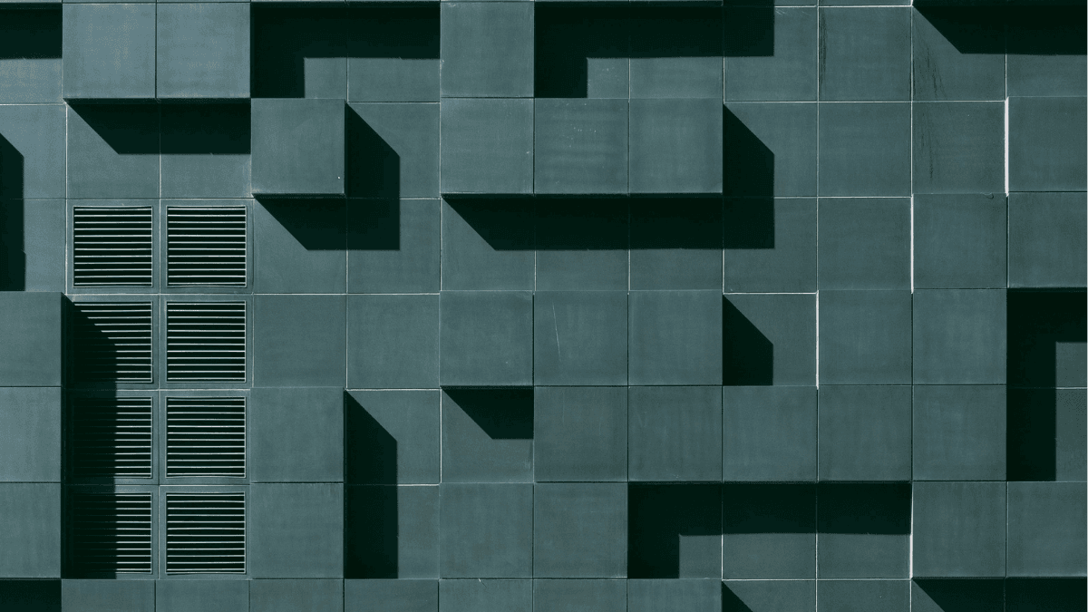 Abstract architectural wall of teal blocks and shadows.